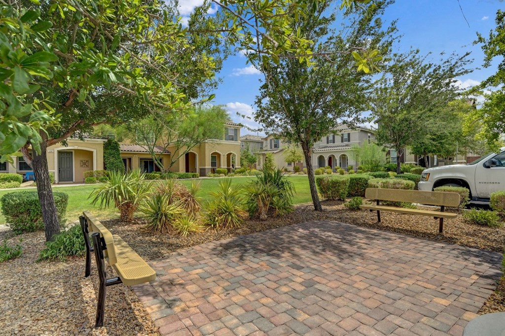 a park with a bench and trees in front of a house