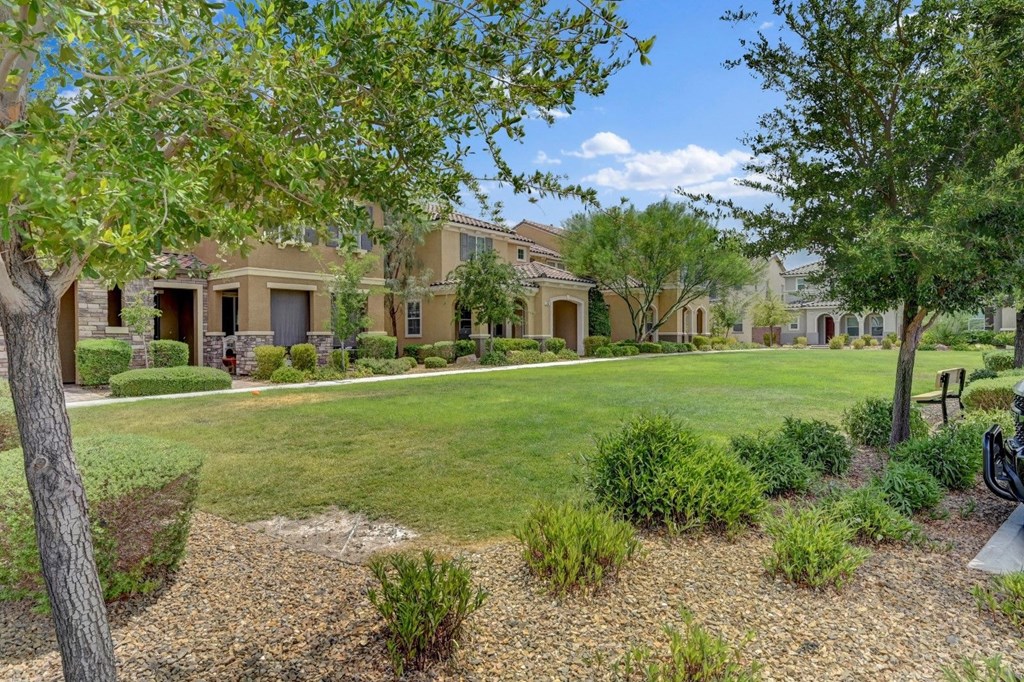 a large lawn in front of a house with trees