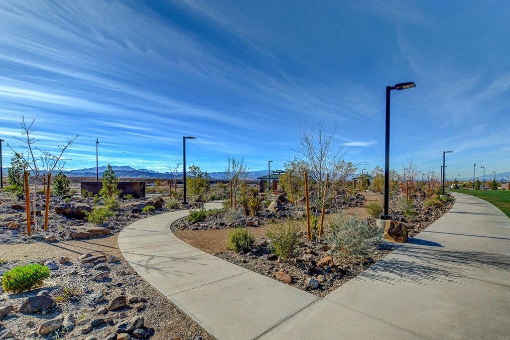 a sidewalk in a garden with mountains in the background