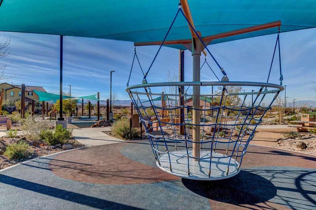 a metal bird cage hanging from a swing in a playground