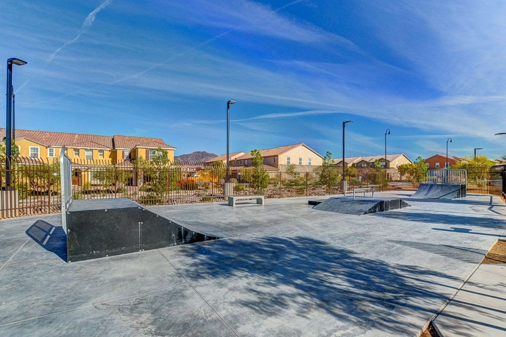 a skate park with a fence and houses in the background