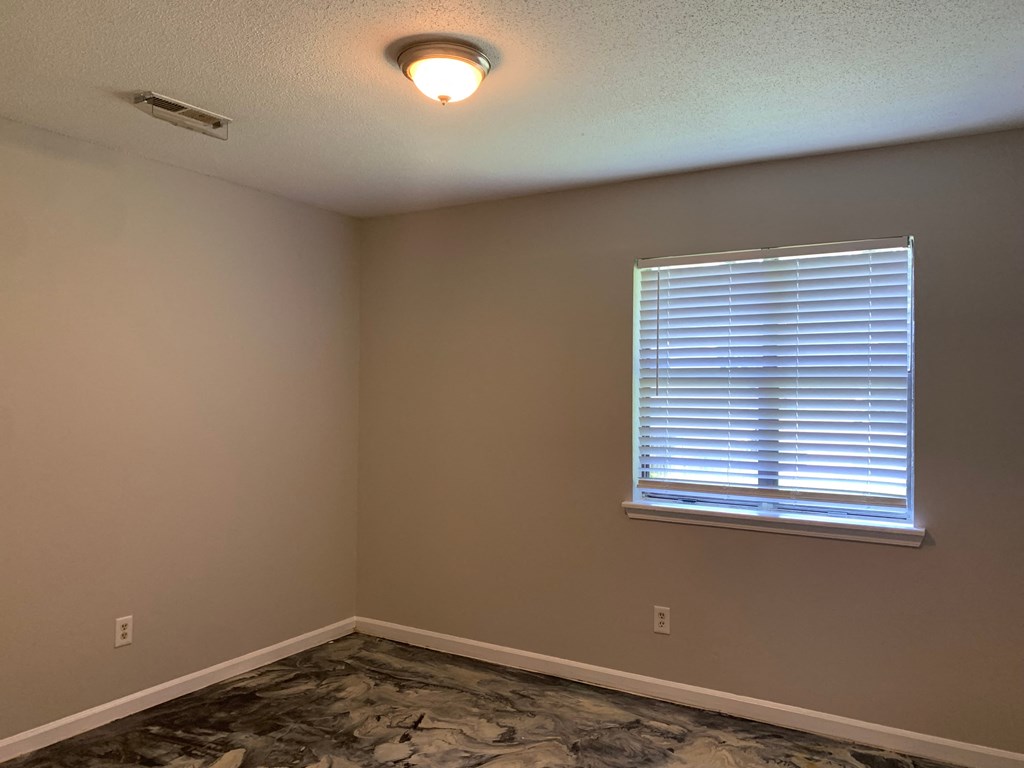 an empty room with a window and a lamp on the ceiling