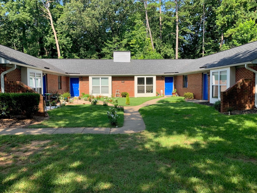 a small brick house with blue doors and a lawn