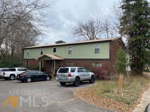 a green house with cars parked in a parking lot