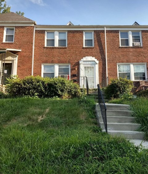 the front of a brick house with stairs in front of it