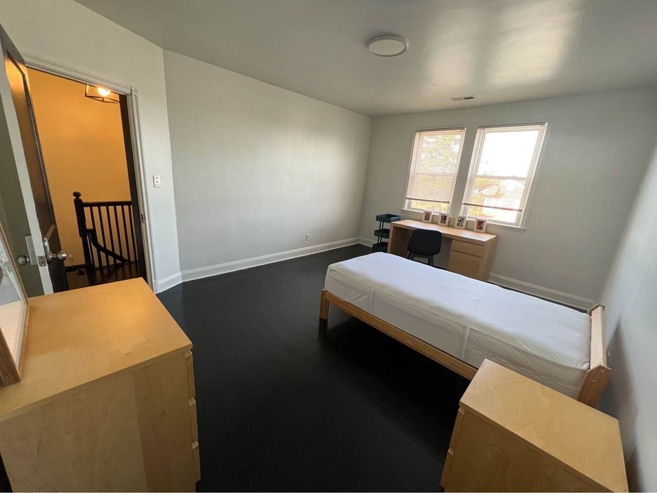 a bedroom with a bed and a desk and a window