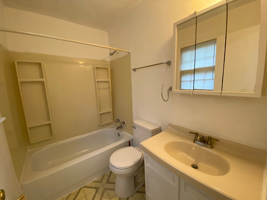 A white bathroom with a toilet, sink, and bathtub.