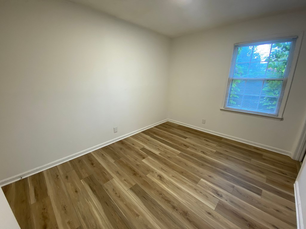 A room with wooden flooring and a window.