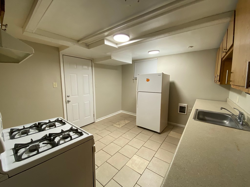 A kitchen with a stove, refrigerator, and sink.