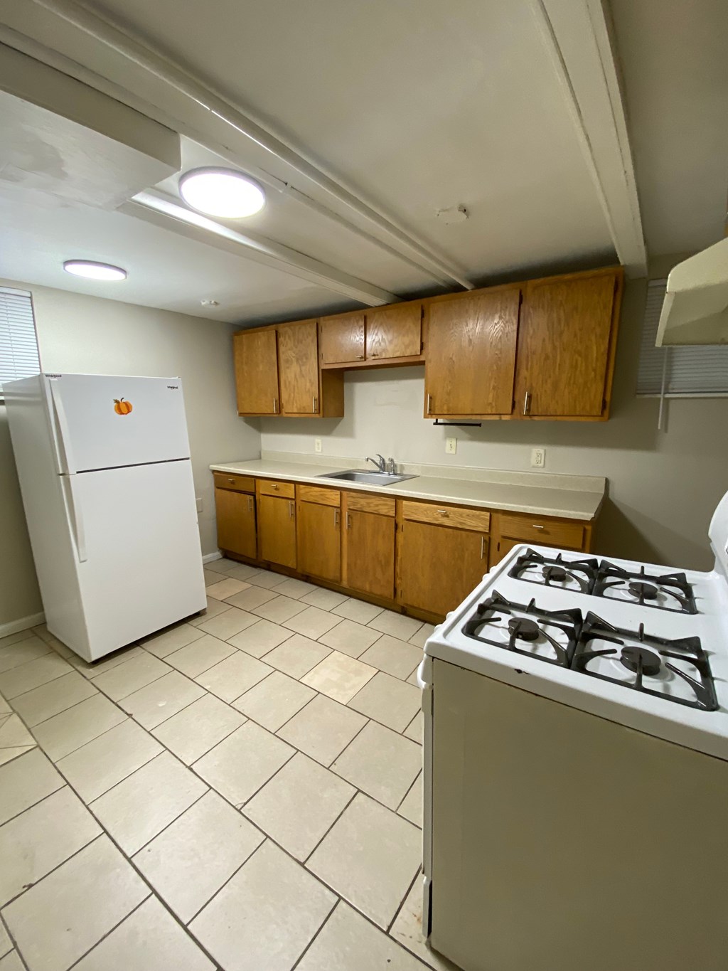 A kitchen with a white fridge, white stove, and brown cabinets.