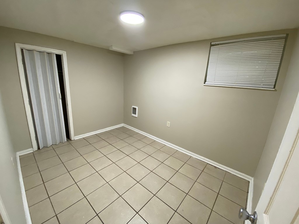 A room with tiled flooring and a door with a window.