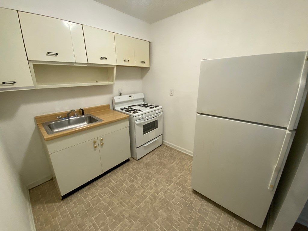 A kitchen with a white refrigerator, sink, and stove.