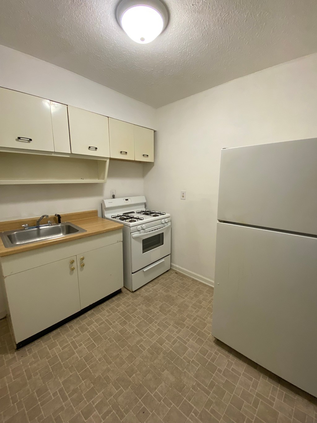 A kitchen with white appliances and beige cabinets.