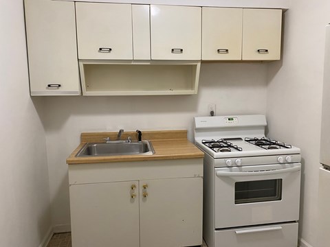 A small kitchen with a white stove and a white sink.
