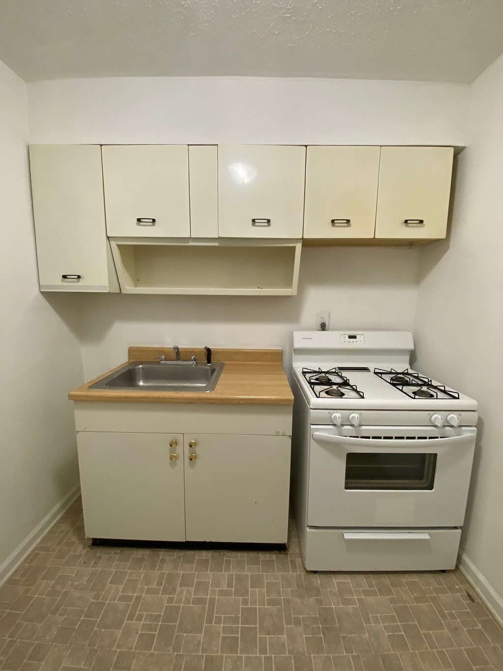 A small kitchen with a stove, sink, and cabinets.