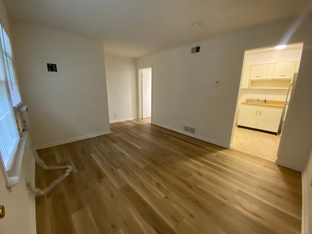 A room with wooden flooring and white walls.