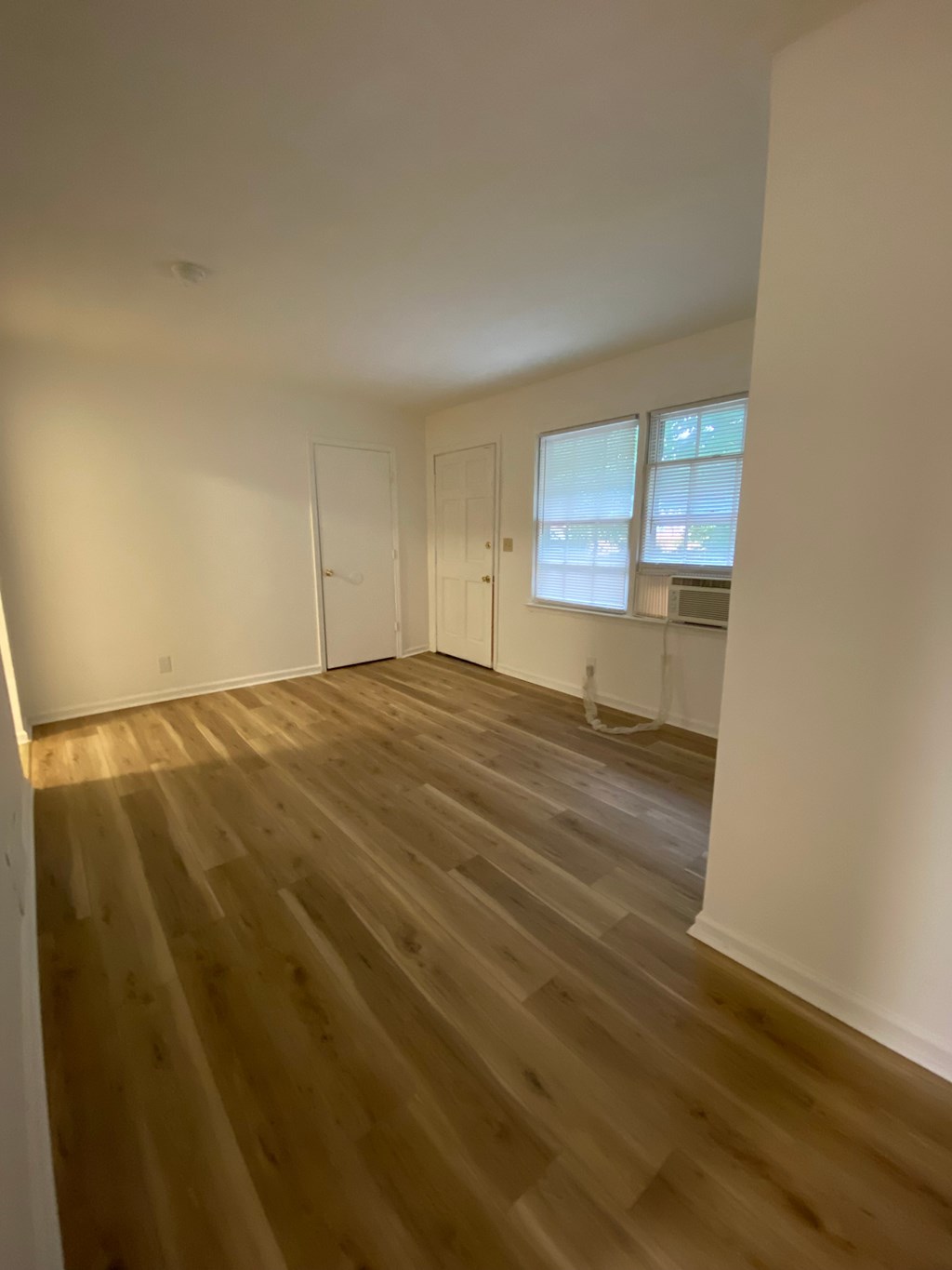A room with wooden flooring and white walls.