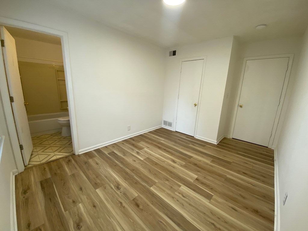 A room with wooden flooring and white walls.