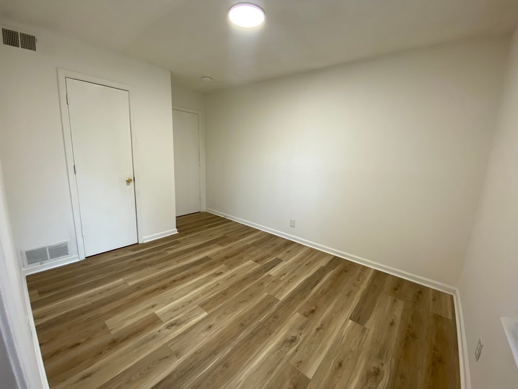 A room with wooden flooring and a white door.