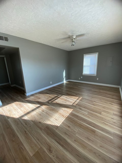 A room with wooden flooring and a ceiling fan.