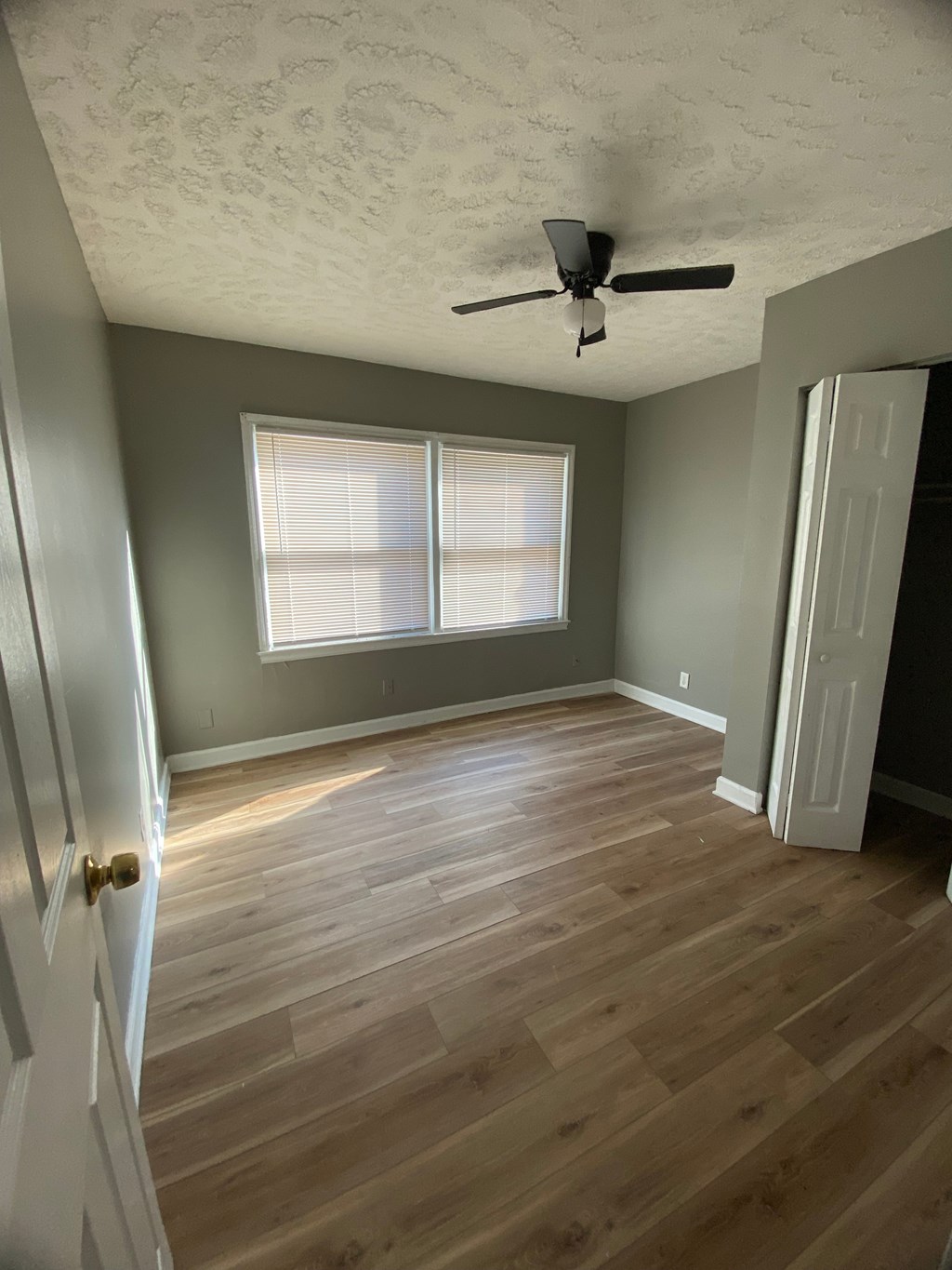 A room with a ceiling fan and wooden flooring.