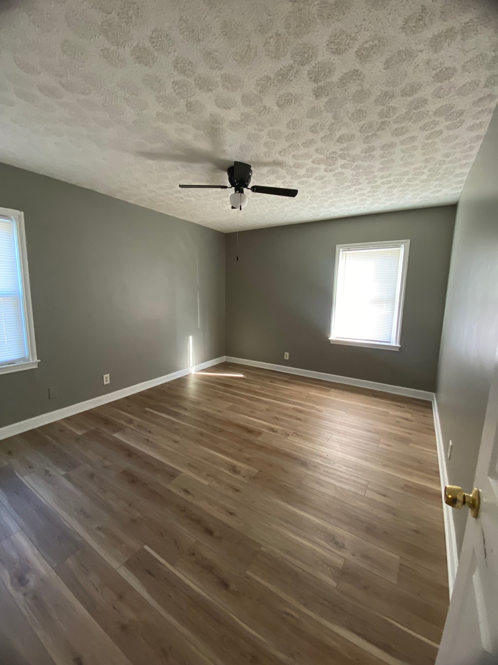 A room with a ceiling fan and wooden flooring.