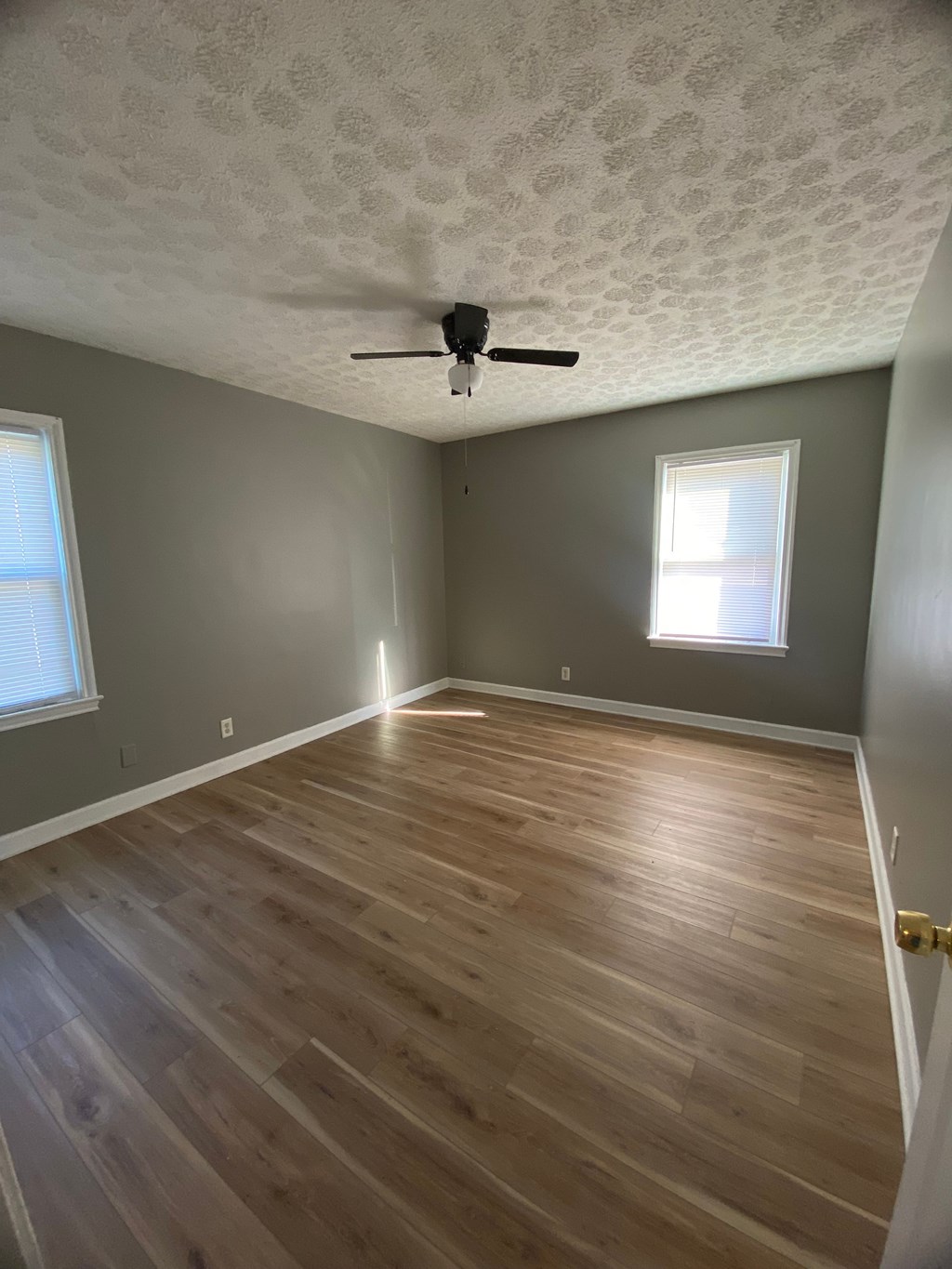 A room with wooden flooring and a ceiling fan.