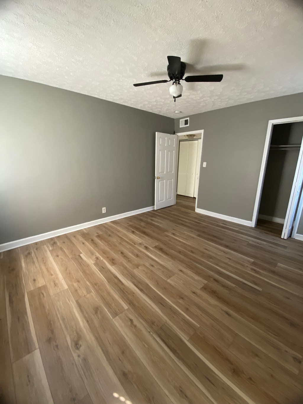 A room with a ceiling fan and wooden flooring.