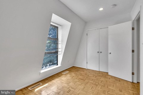 a bedroom with a large window and wooden floors