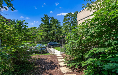 a pathway leading to a yard with a car and a fence