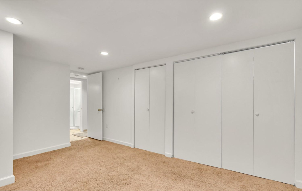 a bedroom with white closets and carpeting