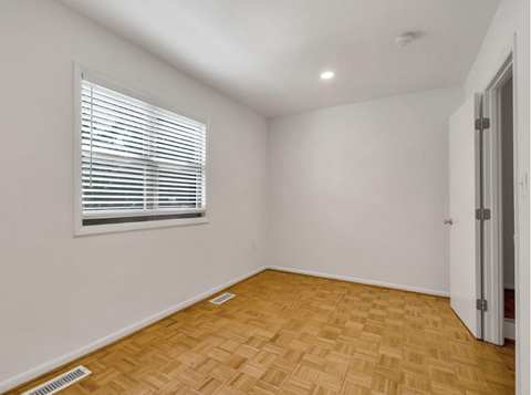 an empty room with a window and wooden floors