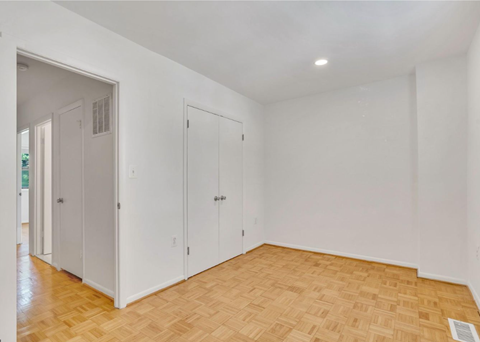 a living room with white walls and wood floors     and a closet