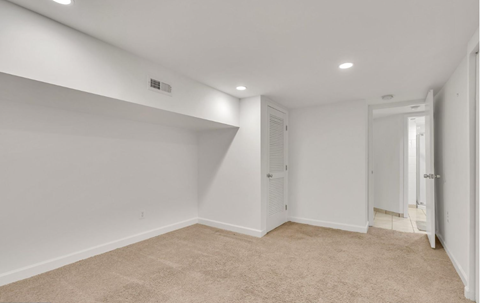 a bedroom with white walls and carpet and a closet