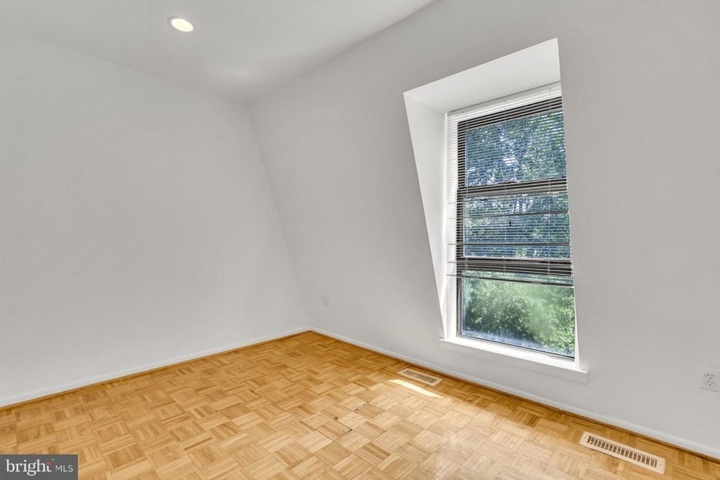 an empty room with a window and wooden floors
