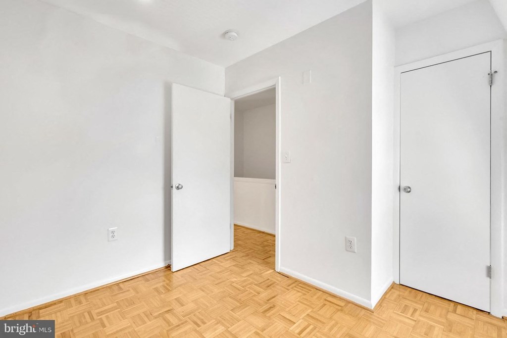 an empty room with white walls and a wooden floor and two doors