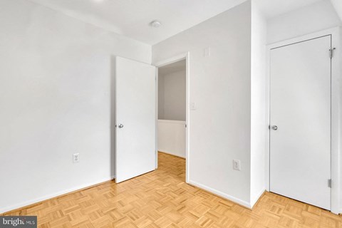 an empty room with white walls and a wooden floor and two doors