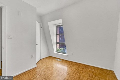 an empty room with a window and wooden floors