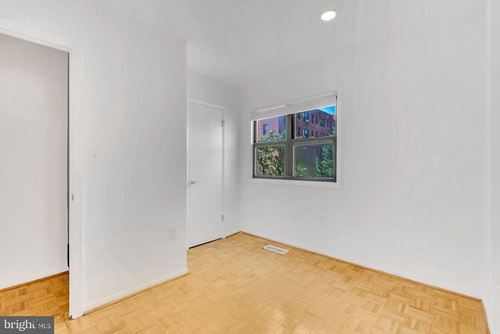 a white room with a window and wooden floors