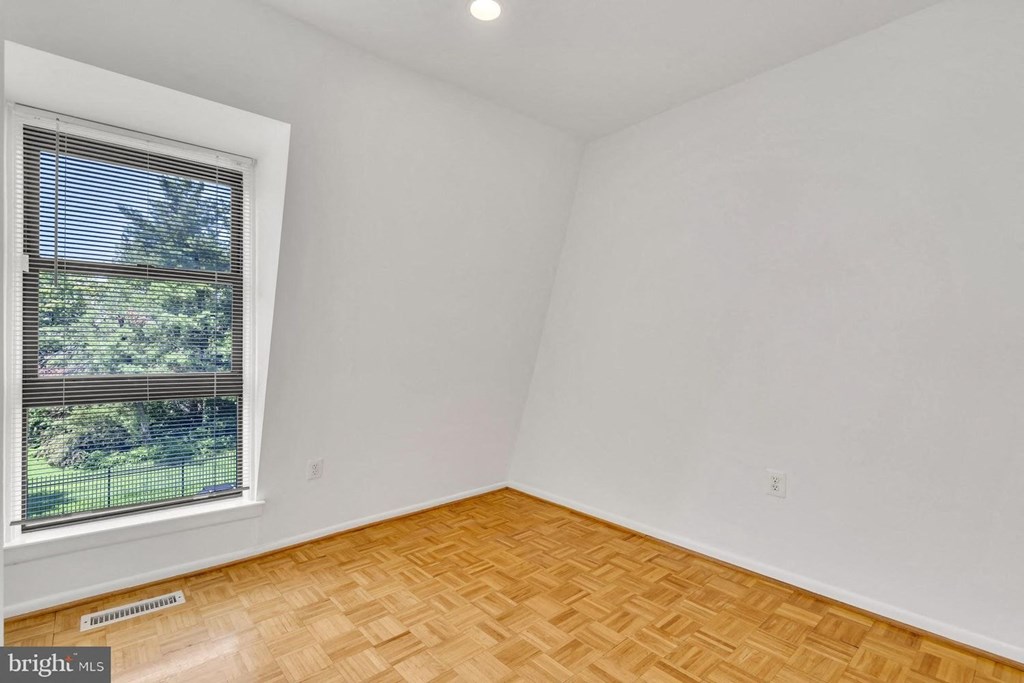 an empty room with a window and wooden floors