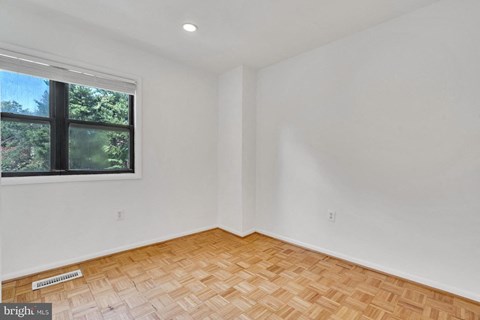 an empty room with a window and wooden floors