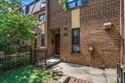 the front of a brick house with a yard and a backdoor