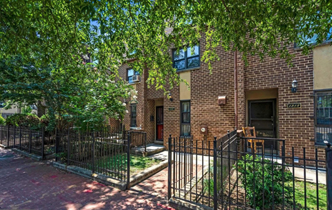 a brick apartment building with a yard and a wrought iron fence