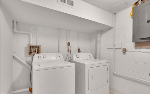 a white laundry room with two washes and a dryer