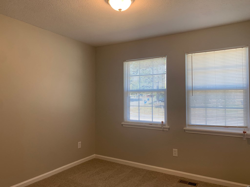 a bedroom with two windows and a carpeted floor