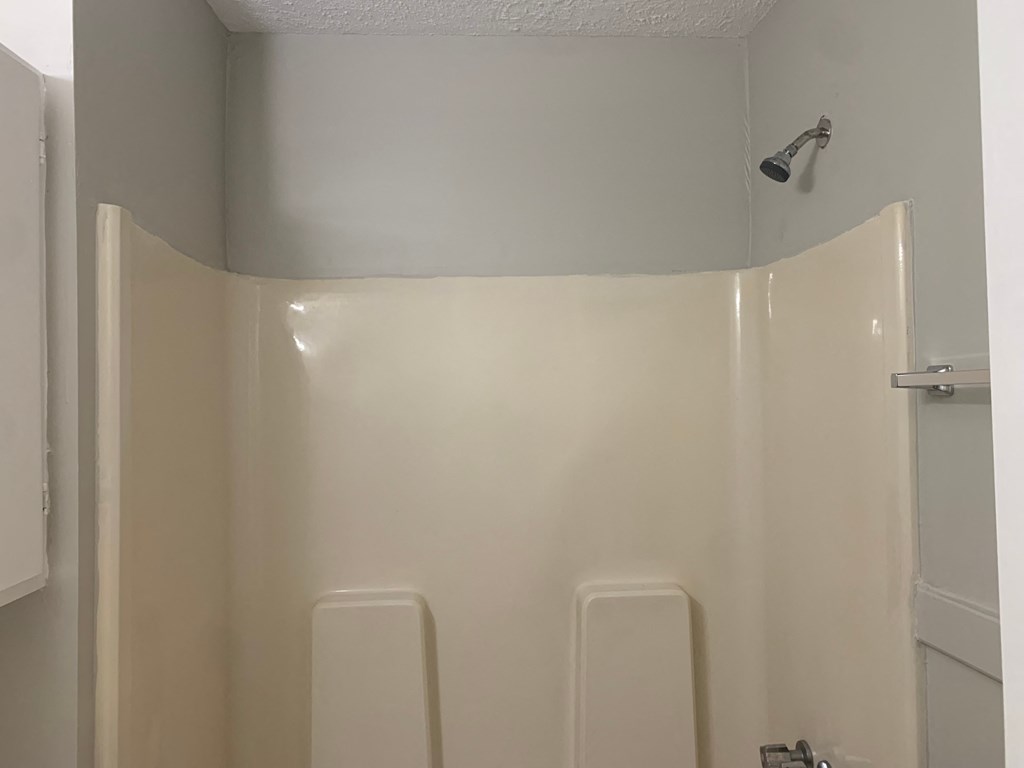 a bathroom with a shower and a white wall