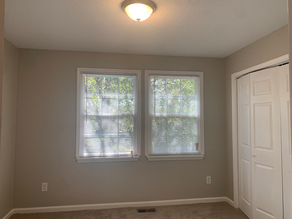 an empty room with two windows and a door