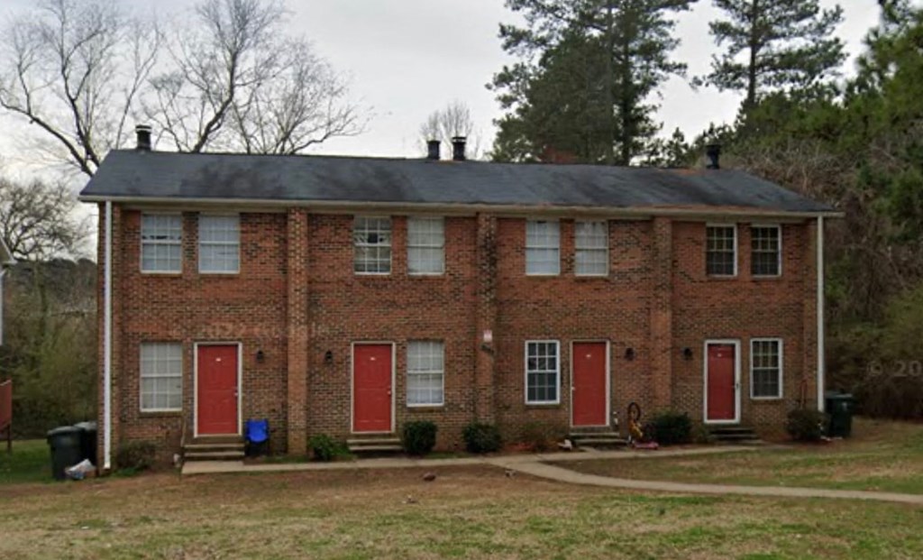 a red brick house with red doors and a black roof
