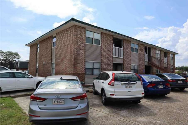 an apartment building with a parking lot full of cars