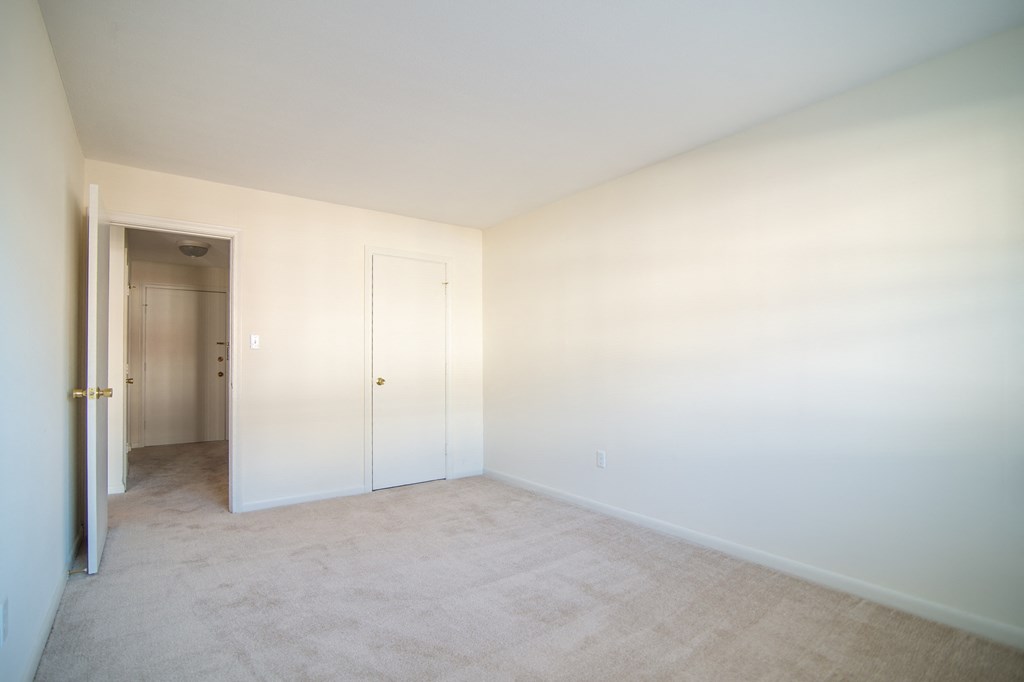 an empty room with white walls and a door to a closet